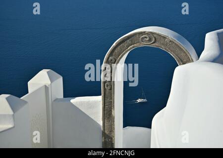 Scenic landscape with view of a Catamaran sailing on the waters of Aegean Sea as seen through a stone archway in Santorini, Cyclades Greece. Stock Photo