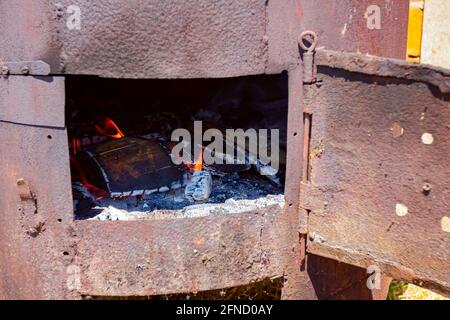 Fire flames are igniting and burning, blazing in the old rusty firebox. Stock Photo