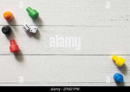 Multi-colored game chips with dices on wooden board. Board game. Stock Photo