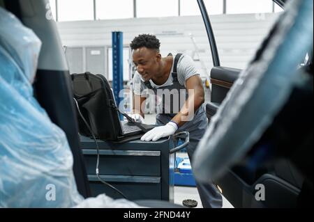 Male mechanic using laptop, car service Stock Photo