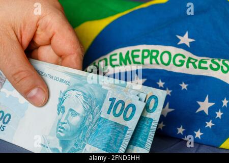 Brazilian money, one hundred reais banknotes on the background of the national flag. Country economy concept Stock Photo