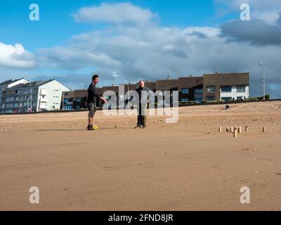 Courseulles sur Mer France May 2021. Playing the Scandinavian Molkky kubb game on the beach. Wooden blocks standing on the beach and two men play Stock Photo Alamy