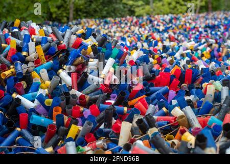 Many colorful spent shotgun shells displayed in front of a shooting range in the UK. Many different colors and gauges, concepts of clay shooting, war, Stock Photo