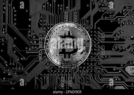 Bitcoin cryptocurrency token coin against circuit board background in black & white Stock Photo