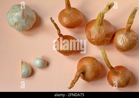 Top view of onion and garlic bulbs on pastel beige background. Stock Photo