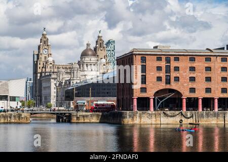 Canoes in the Albert Dock seen in May 2021 against the stunning backdrop of the Three Graces on the Liverpool skyline.