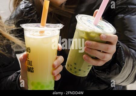 A closeup of two women holding plastic transparent cups of bubble milk tea Stock Photo