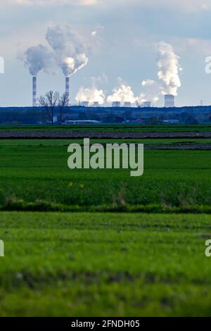 A view of the smoking chimneys of a distant coal-fired power plant on the horizon. Photo taken in natural daylight, late afternoon. Stock Photo