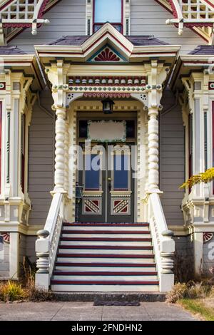 Victorian era gingerbread trimmed home entrance with steps up to front door and painted bric a brac Stock Photo