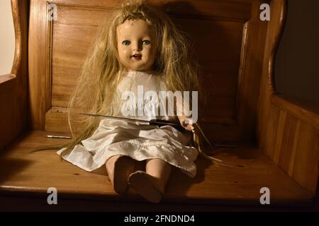 A closeup of a creepy old doll on the wooden chair Stock Photo