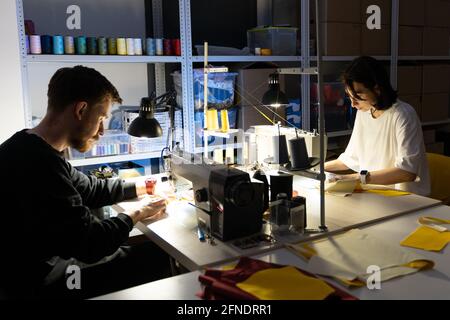 Two tailors sew on sewing machines in atelier. Team of clothes designers entrepreneurs work together Stock Photo