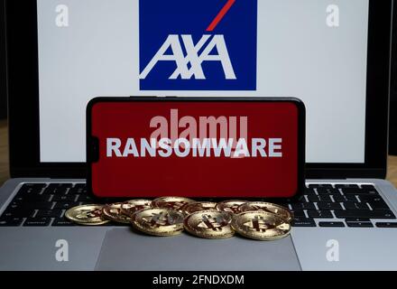 AXA logo on the blurred background and word RANSOMWARE on the smartphone in front. Stafford, United Kingdom, May 16, 2021. Stock Photo