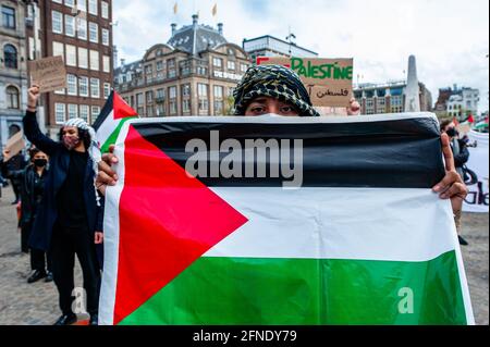 Amsterdam, Netherlands. 16th May, 2021. A protester seen holding a Palestinian flag during the demonstration.The Netherlands and thousands of Dutch people gathered at the Dam Square in Amsterdam to condemn the Israeli attacks and the forced evictions of Palestinians from Sheikh Jarrah neighborhood in occupied East Jerusalem. Credit: SOPA Images Limited/Alamy Live News Stock Photo