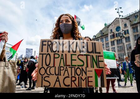 Amsterdam, Netherlands. 16th May, 2021. A protester seen holding a placard against the occupation during the demonstration.The Netherlands and thousands of Dutch people gathered at the Dam Square in Amsterdam to condemn the Israeli attacks and the forced evictions of Palestinians from Sheikh Jarrah neighborhood in occupied East Jerusalem. Credit: SOPA Images Limited/Alamy Live News Stock Photo