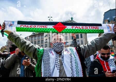 Amsterdam, Netherlands. 16th May, 2021. A protester seen holding a scarf with the Palestinian flag during the demonstration.The Netherlands and thousands of Dutch people gathered at the Dam Square in Amsterdam to condemn the Israeli attacks and the forced evictions of Palestinians from Sheikh Jarrah neighborhood in occupied East Jerusalem. (Photo by Ana Fernandez/SOPA Images/Sipa USA) Credit: Sipa USA/Alamy Live News Stock Photo
