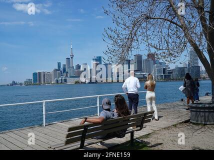 Toronto, Canada - May 16, 2021:  People enjoy a nice day on the waterfront boardwalk, with the downtown skyline in the background. Stock Photo