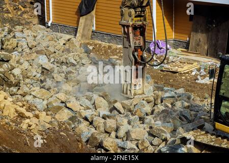Tracked excavator with the jackhammer in a working on smashing rock Stock Photo