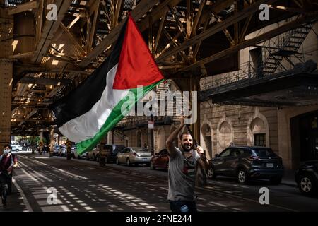 Chicago, USA. 16th May, 2021. A demonstrator carries a Palestinian flag down Lake street in Chicago, Illinois during a march in support of Palestine on May 16, 2021. (Photo by Max Herman/Sipa USA) Credit: Sipa USA/Alamy Live News Stock Photo