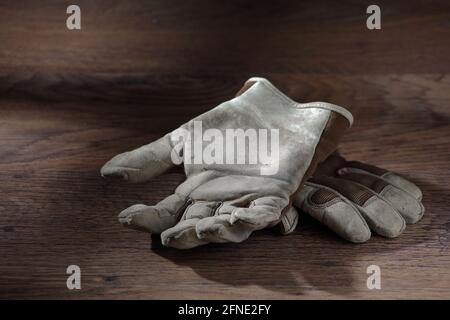 Work gloves on a wood surface with window light