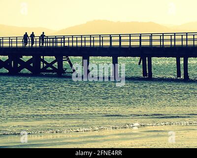 Three summer strollers heading back to the beach on Petone wharf (Wellington, NZ) Stock Photo