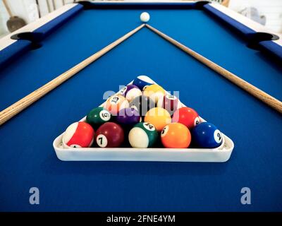 Billiard balls in the white triangle and cue on the blue table. Billiard sport concept. Pool billiard game. Stock Photo