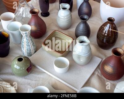 Various colorful ceramic vase arranged on white calico fabric, top view. Empty ceramic vase background. Stock Photo