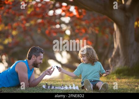 Father and son child playing chess spending time together in park. Stock Photo