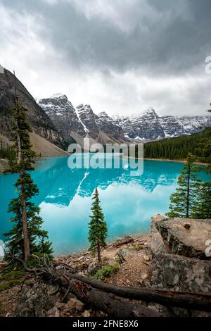 Clouds hanging between mountain peaks, reflection in turquoise glacial lake, Moraine Lake, Valley of the Ten Peaks, Rocky Mountains, Banff National Stock Photo