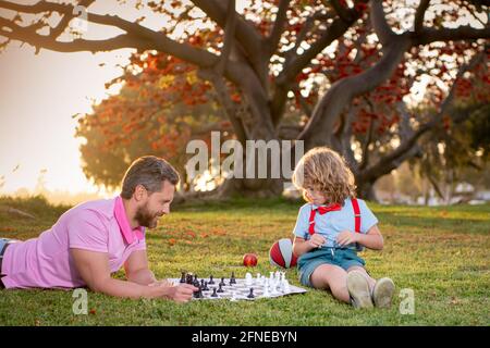 Happy family outdoor. Father and son playing chess in autumn garden. Stock Photo