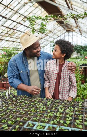 Father talking to his son and teaching him to plant while they working in the farm Stock Photo