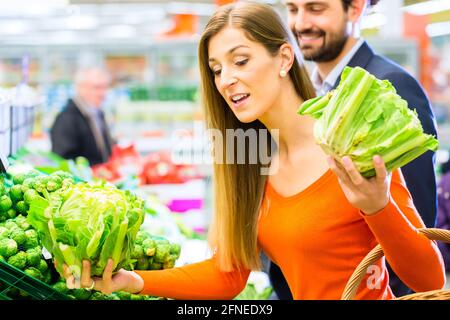 Couple in supermarket at the vegetable shelf shopping for groceries Stock Photo