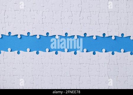 Unassembled white puzzle in middle on dove background Stock Photo