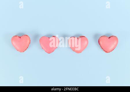 Heart shaped French macaron sweets in a row on blue background Stock Photo