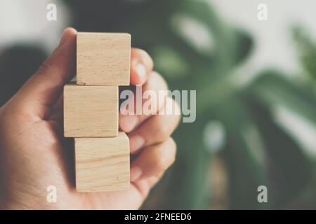 Blank wooden cube that you can put text or icon on in hand hold background Stock Photo