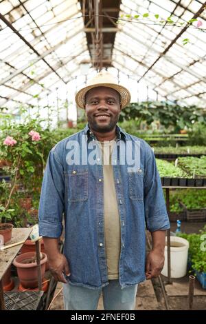 Farmer in straw hat looking at camera while standing in the garden Stock Photo