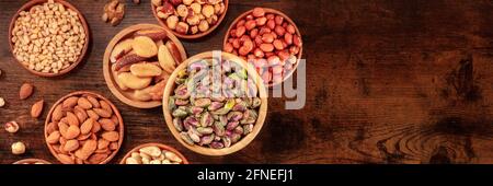 Nuts panorama, top shot with copy space. Many different nuts in wooden bowls Stock Photo