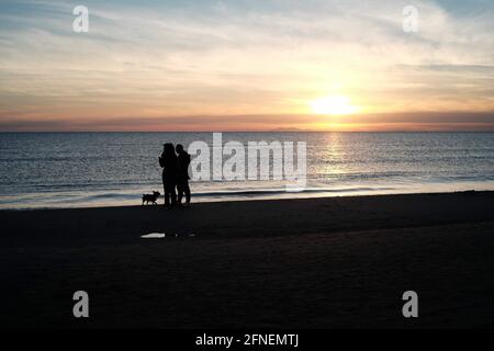 Couple and their dog walking on the beach in Palavas les Flots, near Carnon Plage, Montpellier, Occitanie, South of France Stock Photo