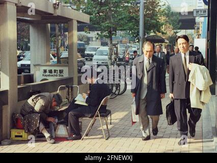 Businessmen in Tokyo. A shoeshine boy serves a customer. [automated translation] Stock Photo