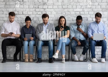 Diverse group of millennial people focused on different devices Stock Photo