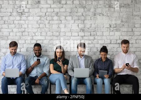 Multicultural team of gadget users sitting in line, using laptops Stock Photo