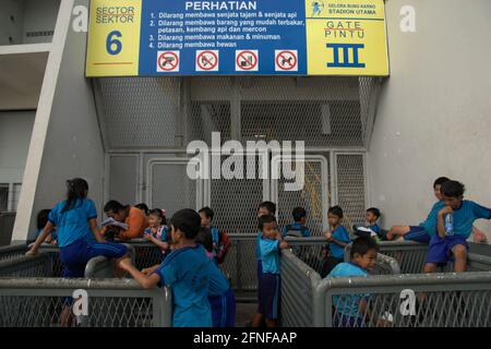 A teacher accompanying elementary students in outdoor learning after sports session outside Senayan Main Stadium (Gelora Bung Karno Stadium) in Jakarta, Indonesia. Stock Photo
