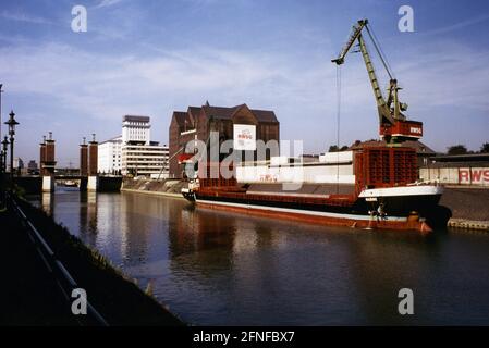 'View of part of the Duisburg inner harbour. On the right side cranes and the granary of the Rheinisch-Westfälische Speditions GmBH (RWSG) Duisburg. Today, the warehouse building houses the state archives of North Rhine-Westphalia. The Swan Gate Bridge can be seen in the background. The area of the inner harbour was rebuilt and modernised as part of the International Building Exhibition in the project ''Working, Living and Living by the Water''. Undated photo. Ca. 1995 because the building exhibition took place in this year. [automated translation]' Stock Photo