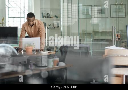 African businessman leaning on his desk and using a laptop Stock Photo