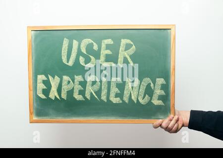 hand holding a chalkboard with the message USER EXPERIENCE handwritten in chalk Stock Photo