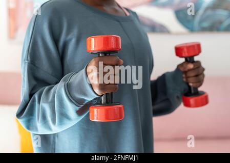Crop black woman doing exercises with dumbbells at home Stock Photo