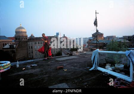 'Berlin-Mitte, DEU, 12.07.1994, man with bedding on the roof of the KULE (Kultur Leben) - house (occupied house in Auguststrasse), in the background the New Synagogue (left) and the Postfuhramt in Oranienburger Strasse, on the right grows ''grass'', (marijuana), [automated translation]' Stock Photo