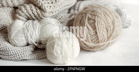 Close-up of balls of yarn in pastel colors and knitted cozy sweater Stock Photo