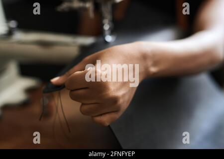 African female artisan sewing leather in her workshop Stock Photo