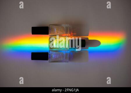 Holographic Nailpolishes in a prism rainbow line on a grey paper Stock Photo