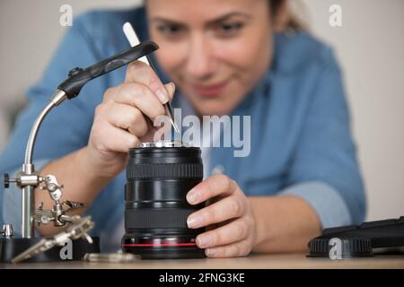 female technician using tweezers on a camera lens Stock Photo